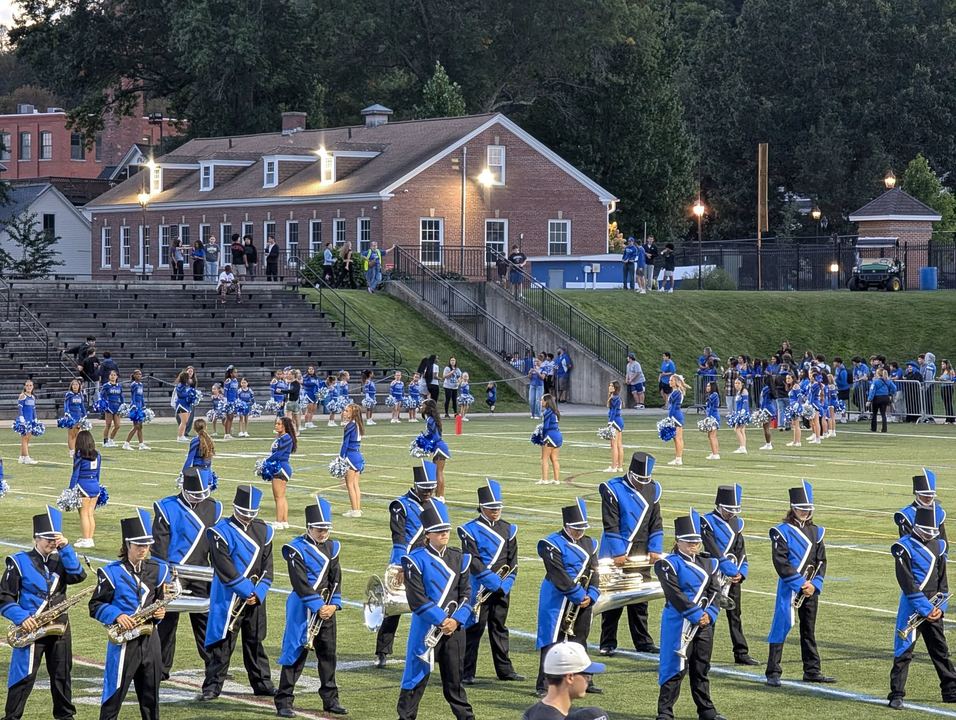 A marching band performing on the field under the lights